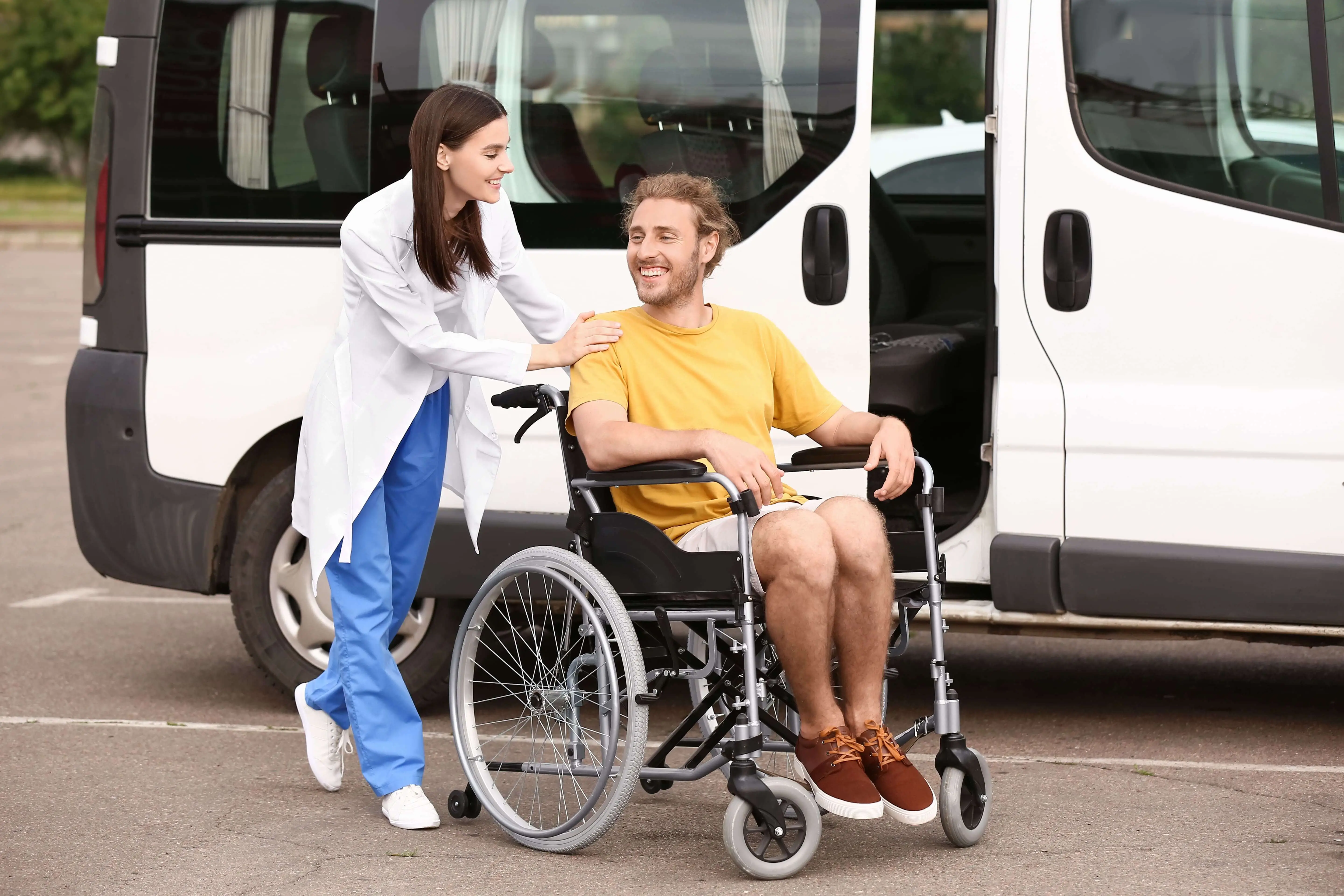 OC HomeCare caregiver assisting smiling male patient in a wheelchair for non-emergency medical transportation in Orange County, CA