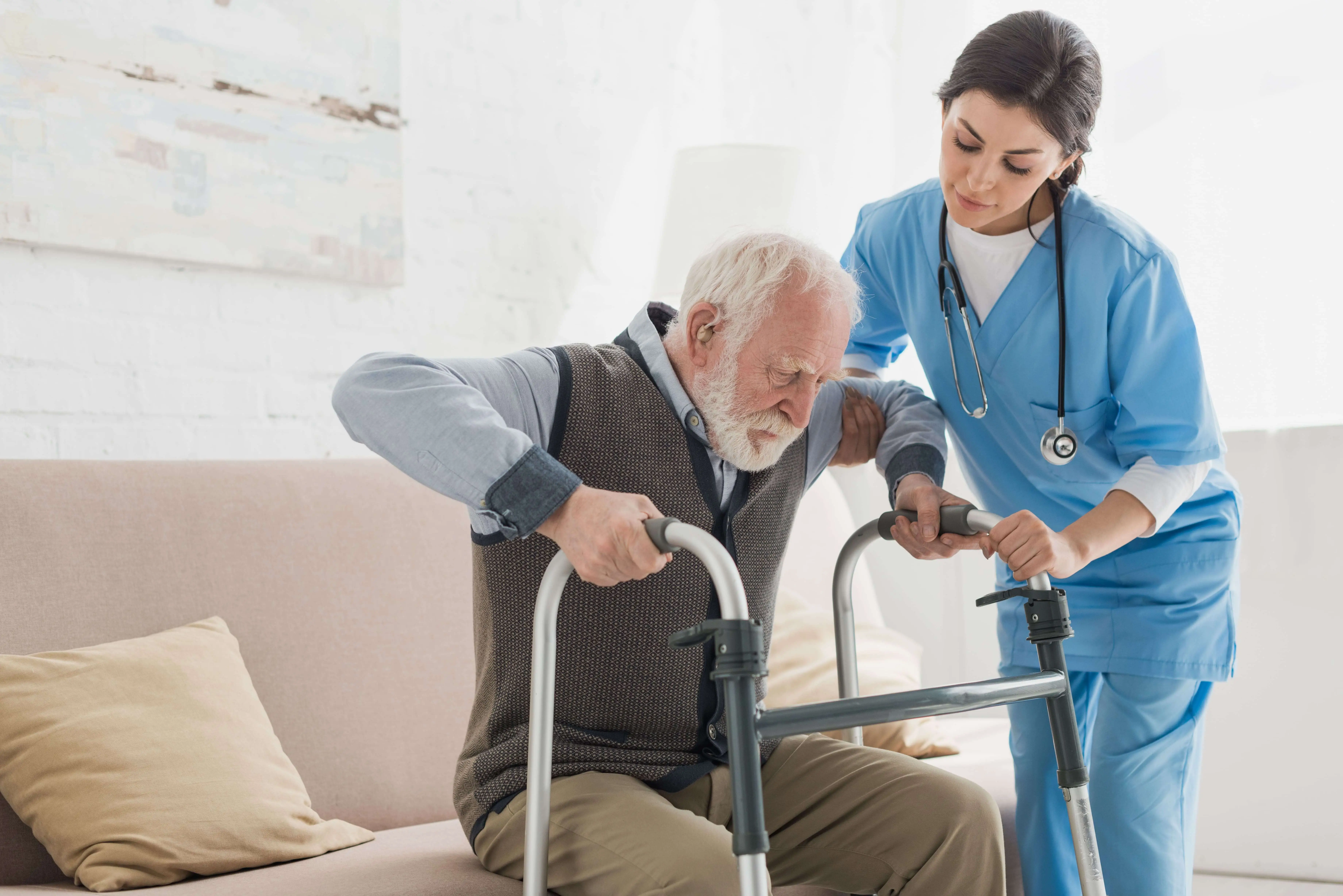 OC HomeCare nurse helping elderly man safely transition using walker at home in Orange County, California