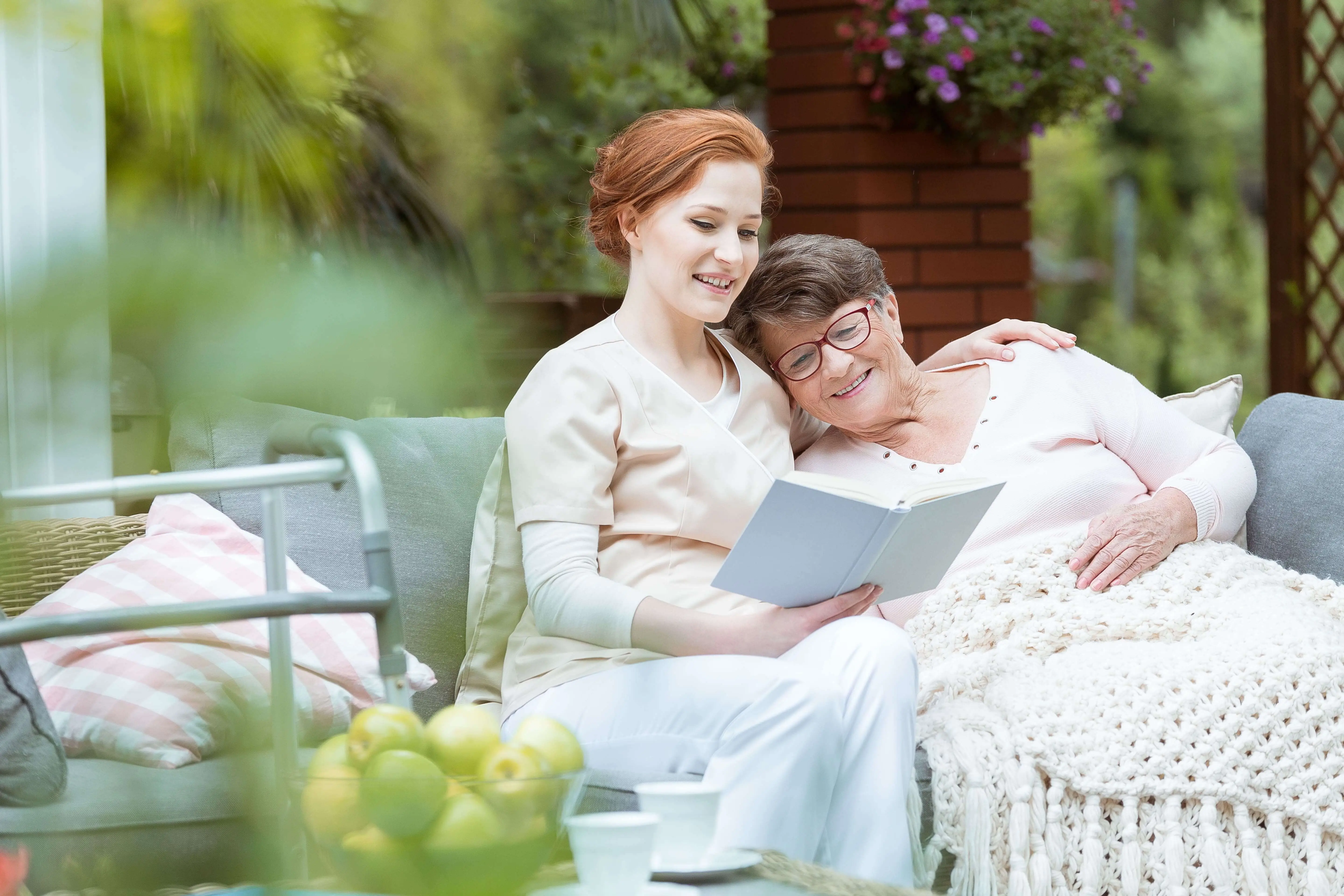 OC HomeCare caregiver offering compassionate senior care in Cypress, CA—reading with a joyful elderly woman in a peaceful outdoor environment