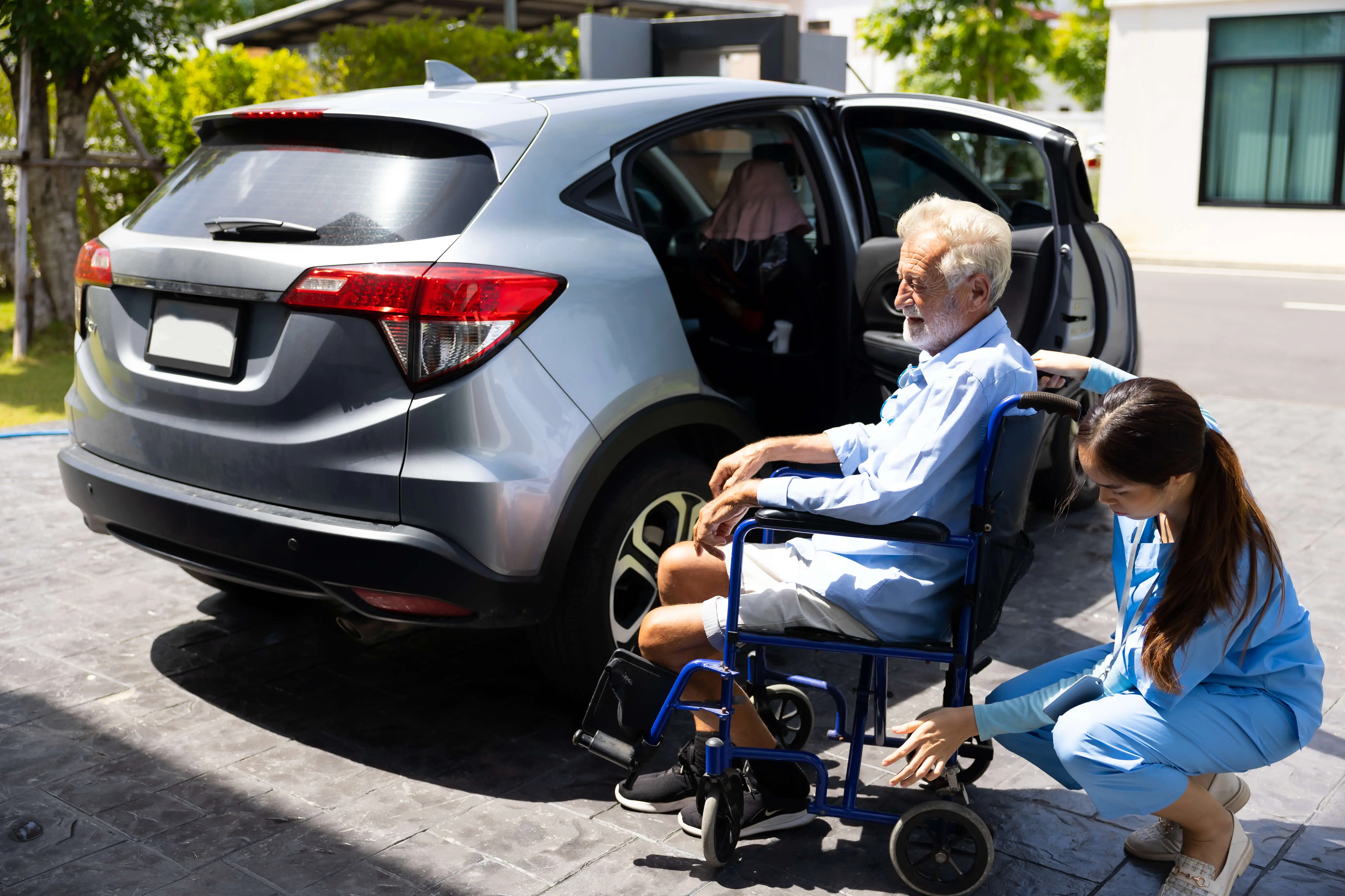 OC HomeCare caregiver assisting senior man in a wheelchair outside a transport vehicle for non-emergency medical transportation in Orange County, CA