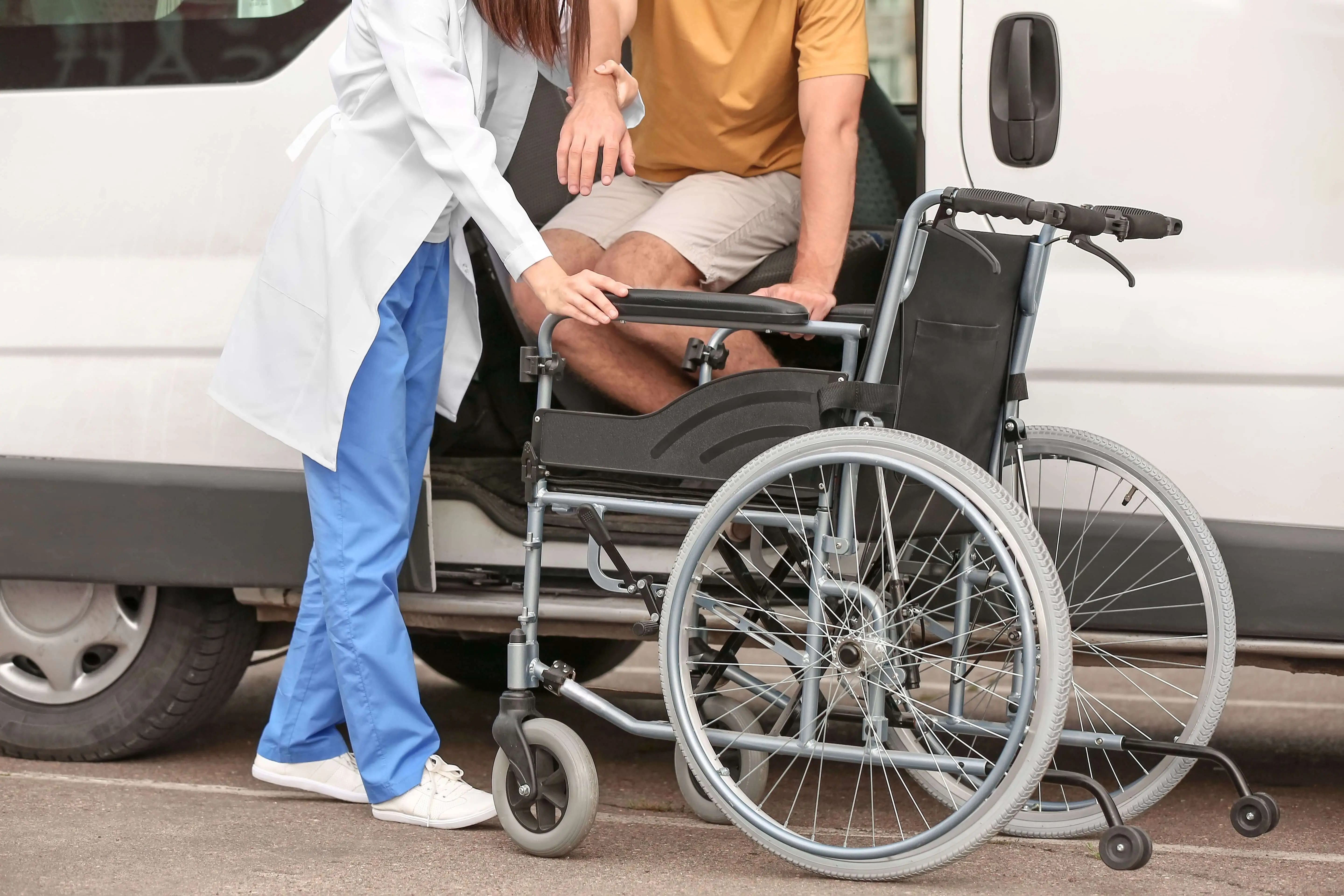 Dedicated caregiver assisting a patient into a wheelchair for safe, non-emergency medical transportation by Safe Link Transport in Orange County, CA